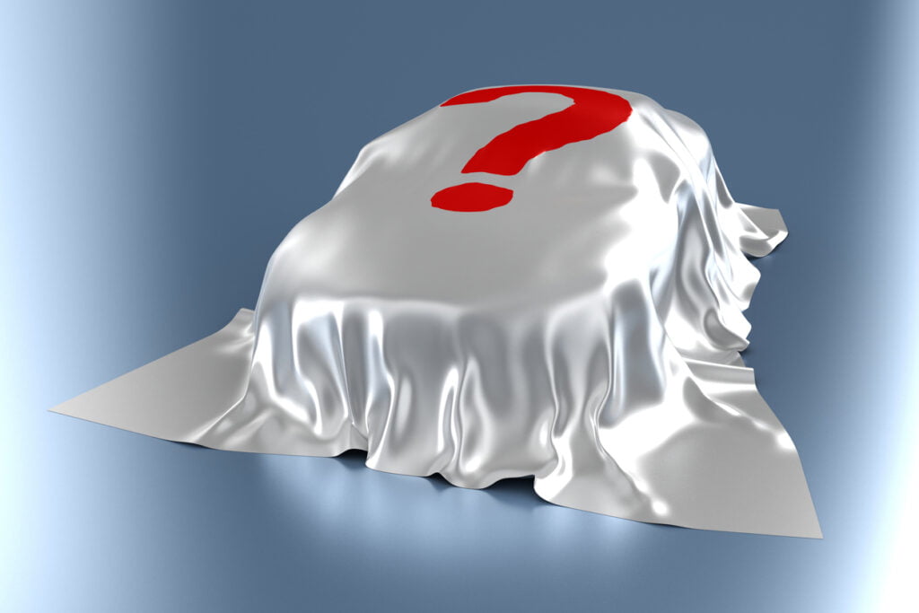 Car hidden beneath a sheet with a red question mark on it.