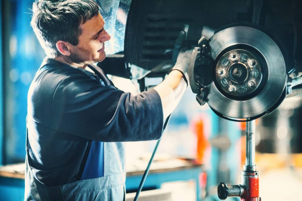 Mechanic installing new brake pads on a vehicle.